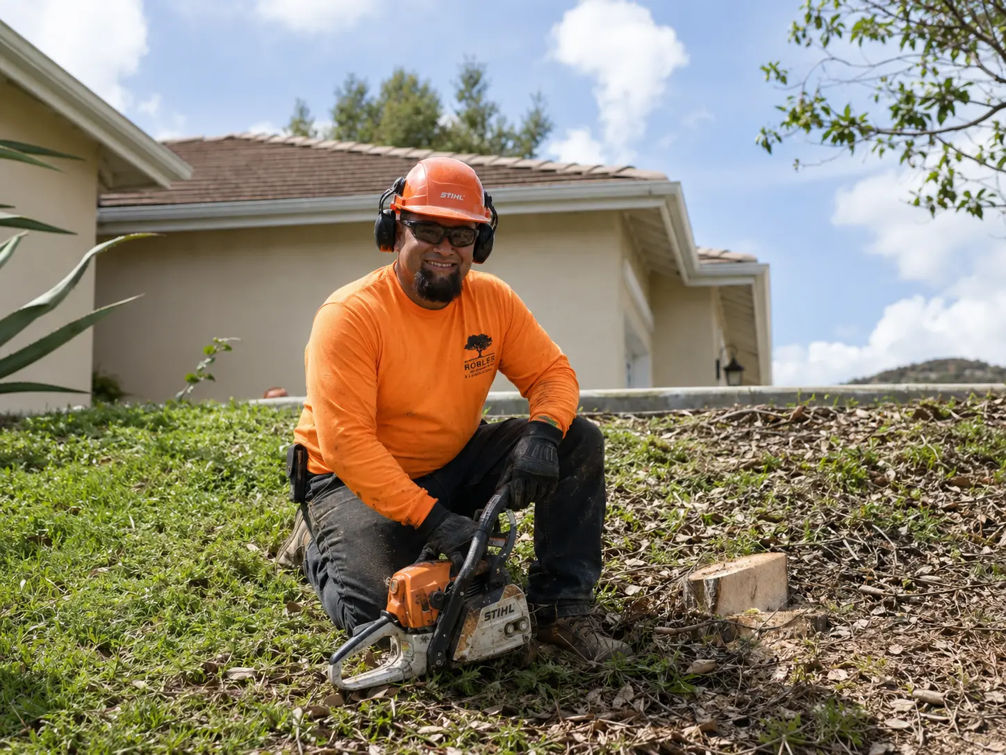 Robles tree care worker in safety gear preparing a chainsaw beside a home
