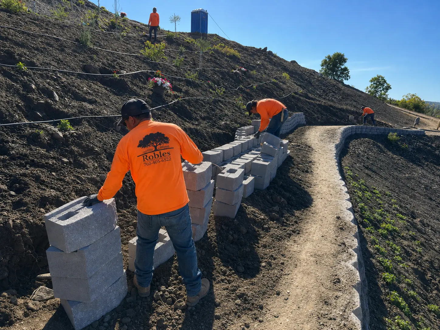 Robles crew installing a curved block retaining wall on a landscaped hillside